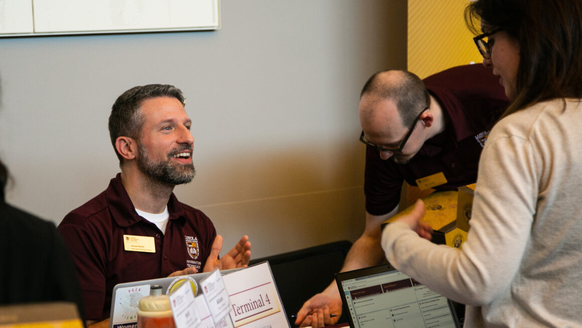 person sitting down and talking to someone standing in front of the table