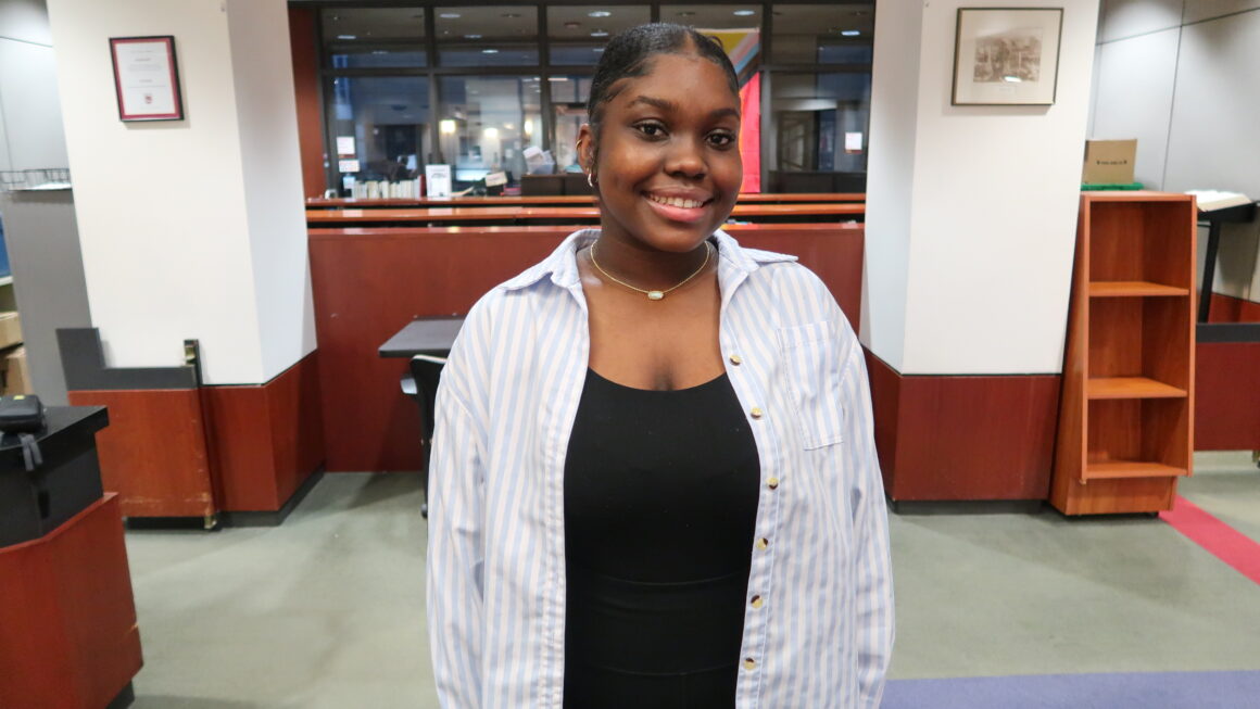 Loyola student, Candace Mack, poses in front of the Lewis Library Circulation Desk