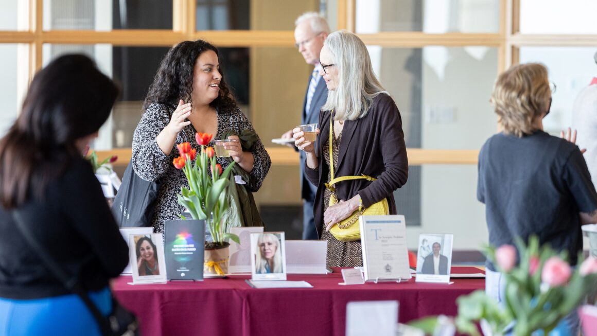 2024 Faculty Scholarship photo of guests in conversation in front of displays of faculty works Photo by Lukas Keapproth from UMC