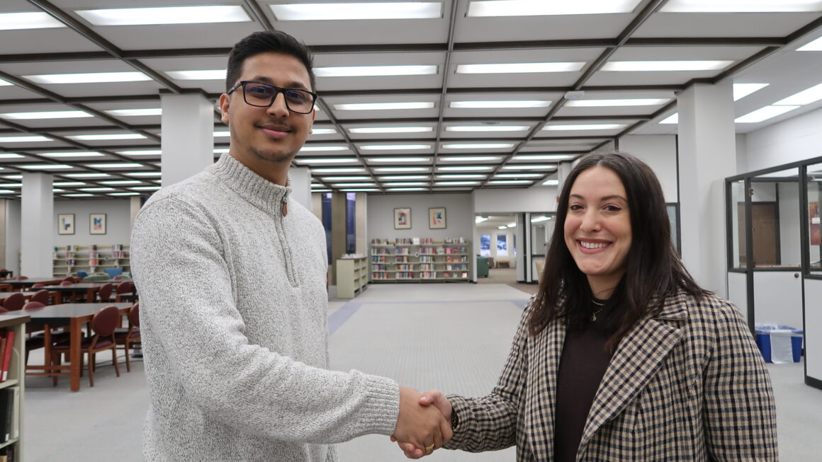 Student worker, Kaushal, standing on the left side shaking hands with Dean Jamie Wittenberg