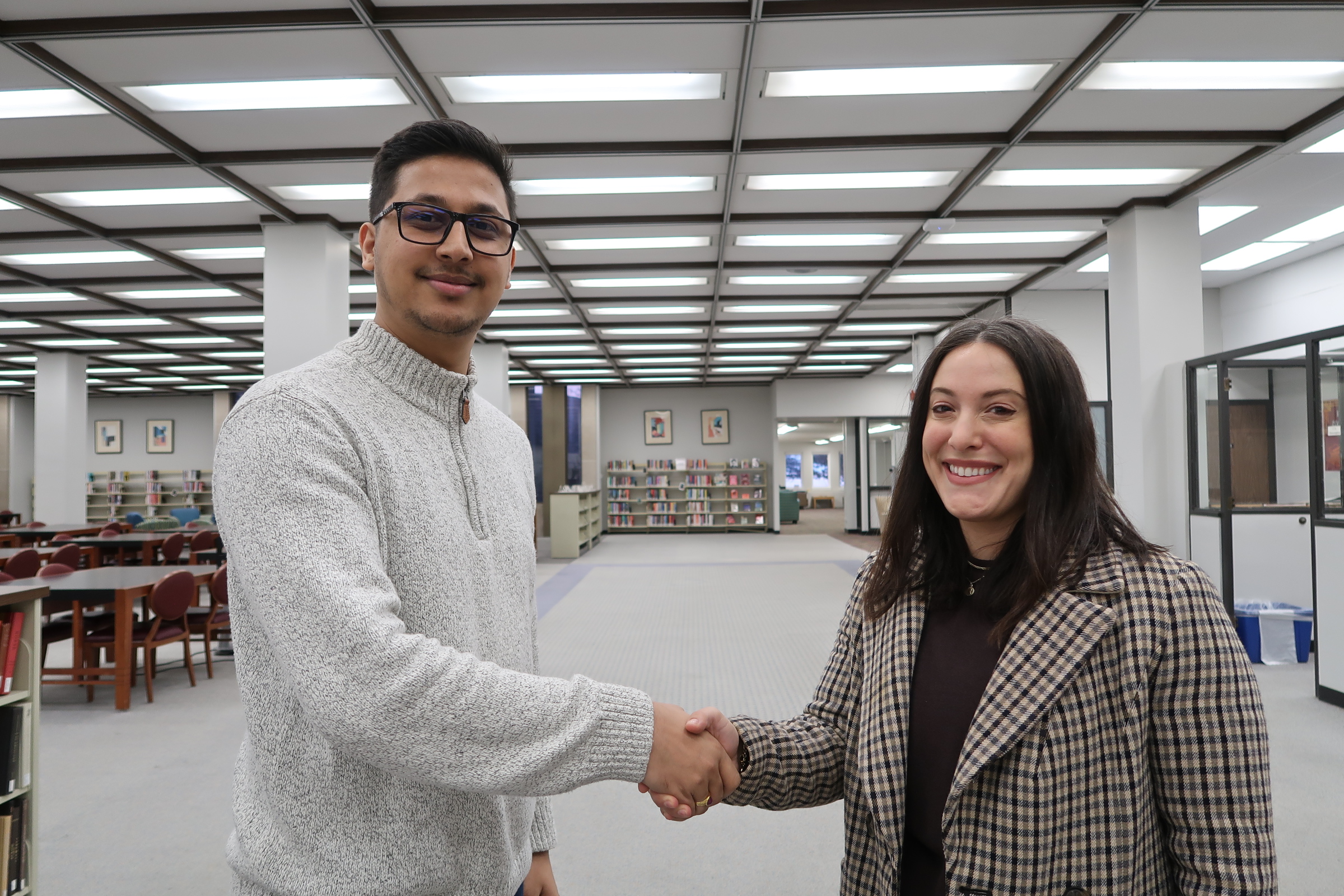 Student worker, Kaushal, standing on the left side shaking hands with Dean Jamie Wittenberg