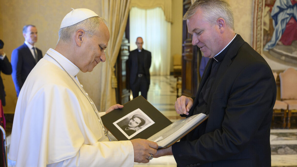 Pope Leo XIV on the left is holding an album showing a black and white photo on the left side. Album is given by the person on the right who is Fr. Tom Neitzke, SJ of Loyola University Chicago.