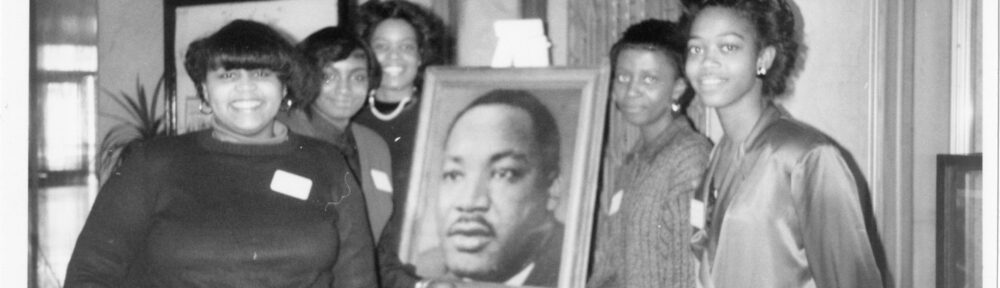 Five individuals posing with a portrait of Martin Luther King, Jr.